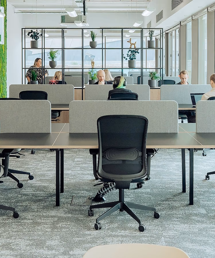 Un plateau de bureaux contemporain : postes alignés, cloisons basses, mur végétal et baies vitrées.