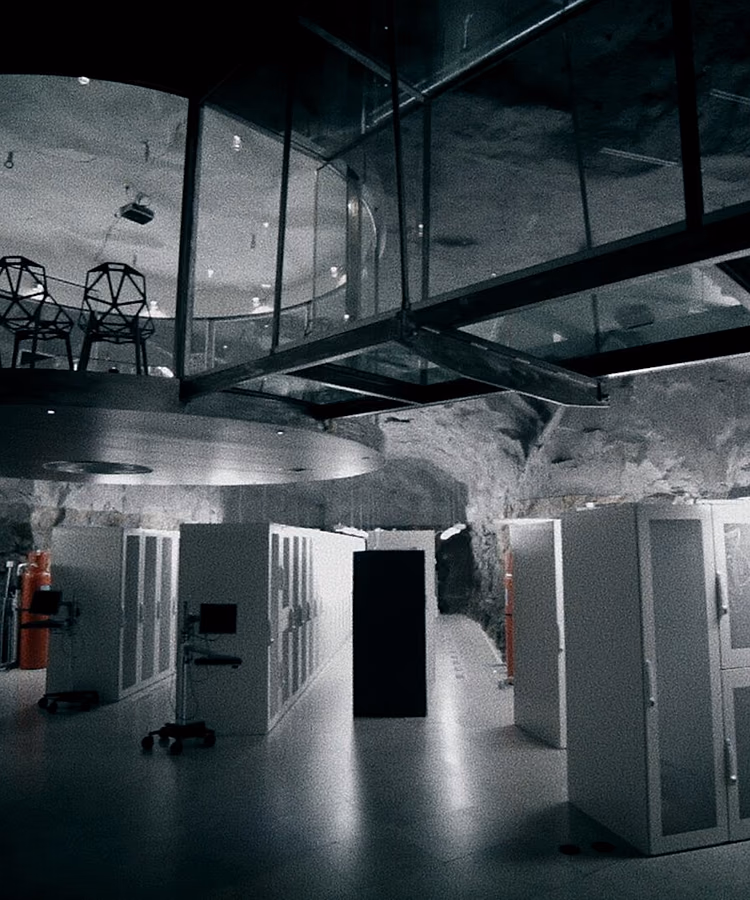 Une salle machine creusée dans la roche : des rangées de baies alignées sous une nef vitrée suspendue.